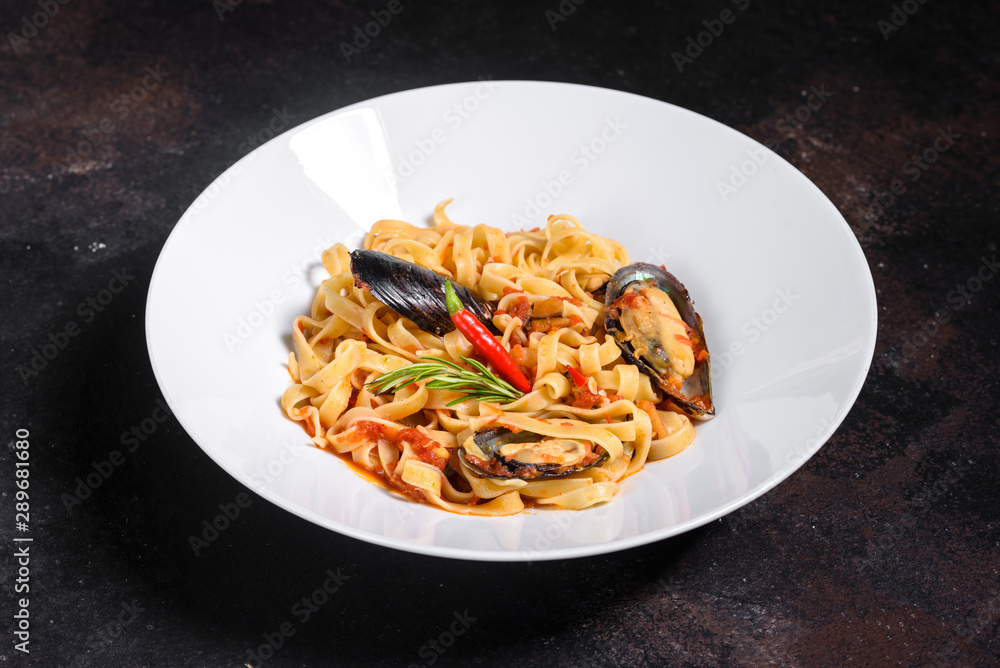 Fototapeta premium Homemade pasta with mussels, sprinkle with chopped parsley and basil. Delicious of pasta with mussel