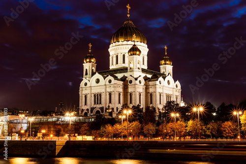 Illuminated Cathedral of Christ the Savior framed with old style street lights of Patriarchy Bridge at night.