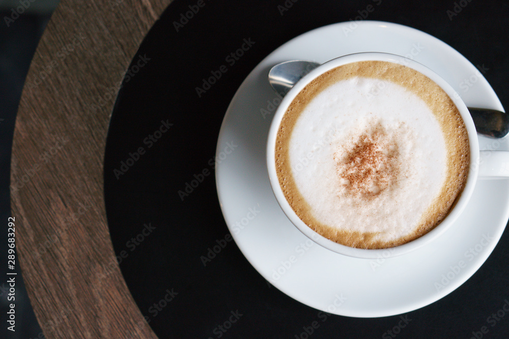 Hot coffee, white cups, plate, spoon all placed on the black - brown circle wooden table. Hot coffee, white cups, plate, spoon all placed on the black - brown circle wooden table.