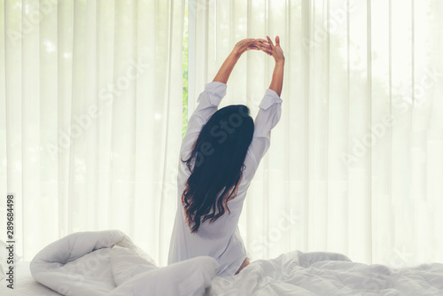 Asian women waking up stretching in bed room at home, early morning time and sunny day, vintate tone.  Lifestyle Concept photo