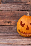 Evil Halloween pumpkin. Scary and angry Halloween pumpkin on rustic wooden background with copy space, cropped image.