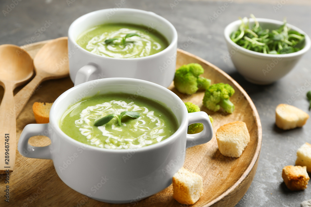 Bowls of delicious broccoli cream soup with microgreens served on tray Bowls of delicious broccoli cream soup with microgreens served on tray