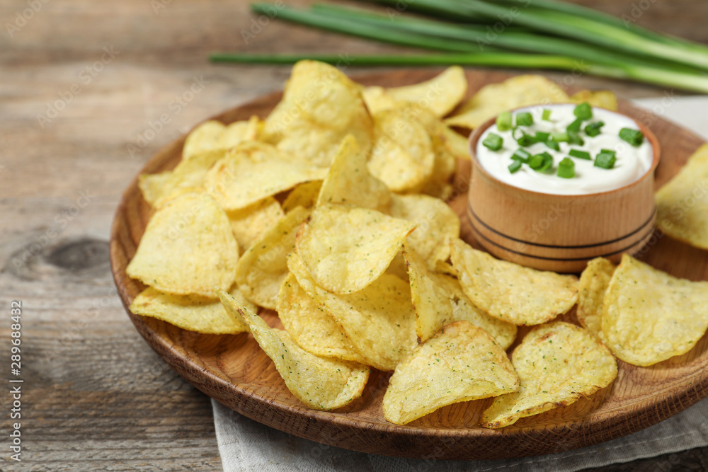 Chips with sour cream on wooden table, closeup