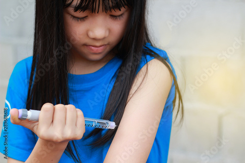 An Asian children girl using insulin pen.Self insulin injection.