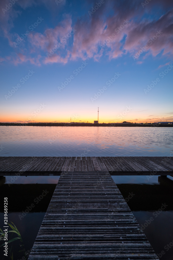 Wooden pier along a river at sunset
