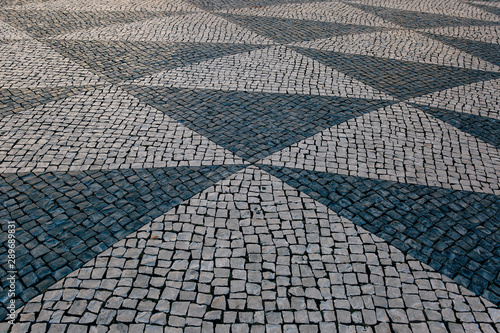 Traditioaal stoneroad, patterned paving tiles in city centre of Lisbon Portugal. photo