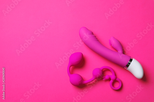 Anal balls and dildo on pink background, flat lay with space for text. Sex toy