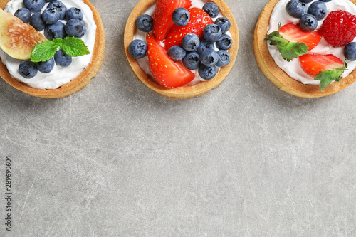 Delicious sweet pastries with berries on grey table  flat lay. Space for text
