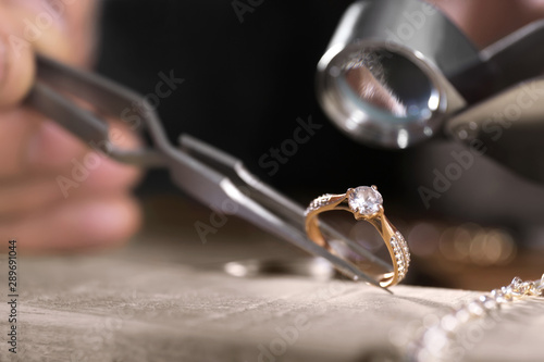 Male jeweler examining diamond ring in workshop, closeup view photo