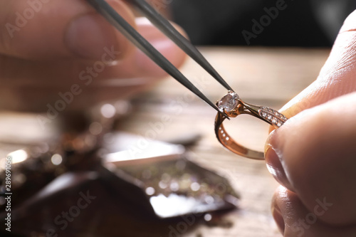 Male jeweler examining diamond ring in workshop, closeup view