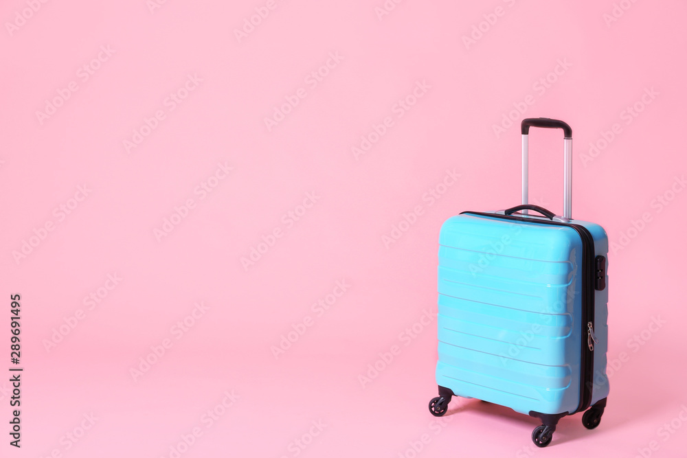Modern blue suitcase on light pink background. Space for text Modern blue suitcase on light pink background. Space for text