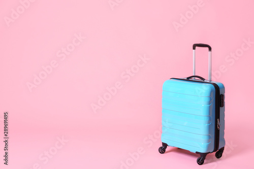 Modern blue suitcase on light pink background. Space for text