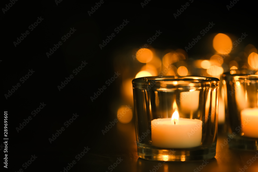 Burning candle on table in darkness, space for text. Funeral symbol Burning candle on table in darkness, space for text. Funeral symbol