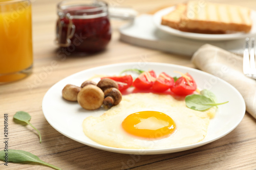 Tasty breakfast with fried egg on wooden table, closeup