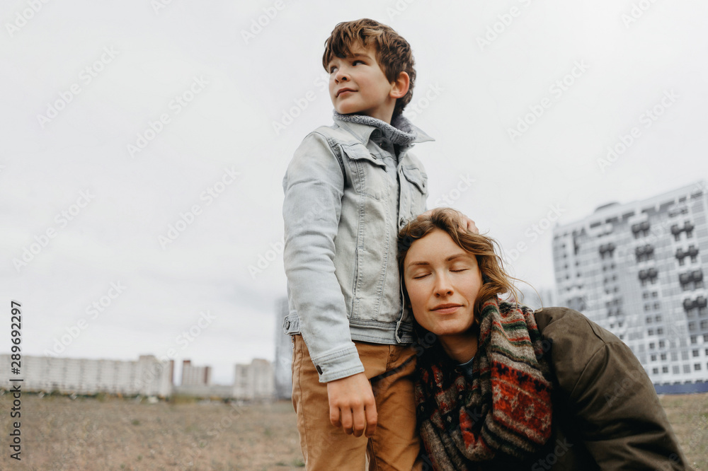 Son hugs his mother. Satisfied mother smiles in the arms of her son