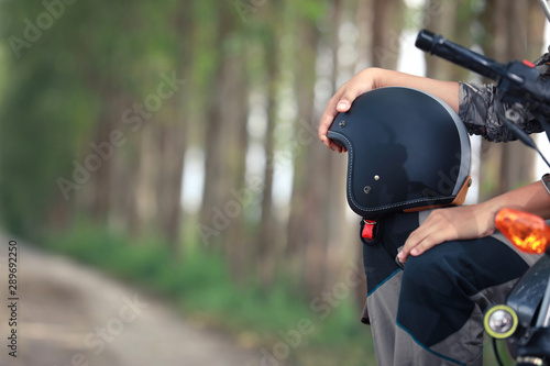 Handsome man is holding a helmet sitting on vintage motorcycle.