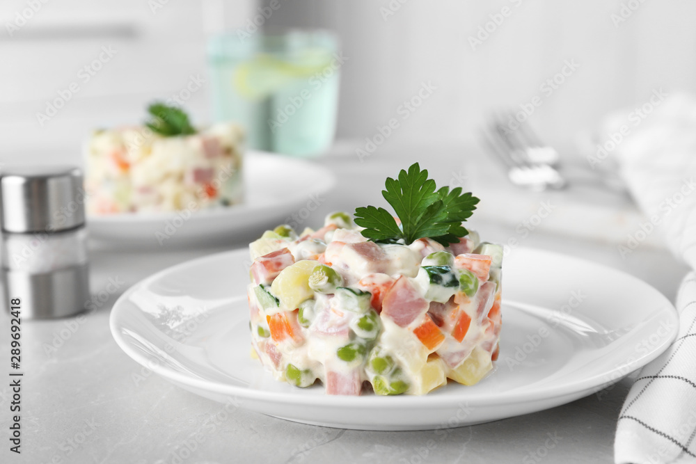Delicious salad Olivier in plate on light table Delicious salad Olivier in plate on light table