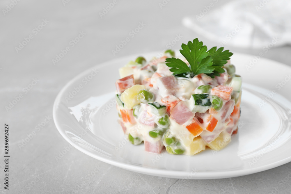Delicious salad Olivier in plate on light table, closeup Delicious salad Olivier in plate on light table, closeup