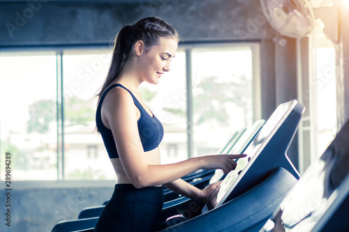 Young woman running on treadmill in the fitness gym.