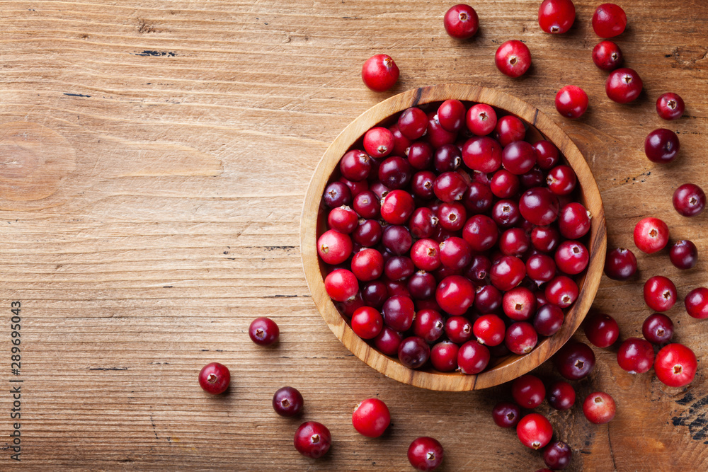 Ripe cranberry in wooden bowl on rustic table top view. - obrazy, fototapety, plakaty 