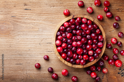 Photography Ripe cranberry in wooden bowl on rustic table top view.