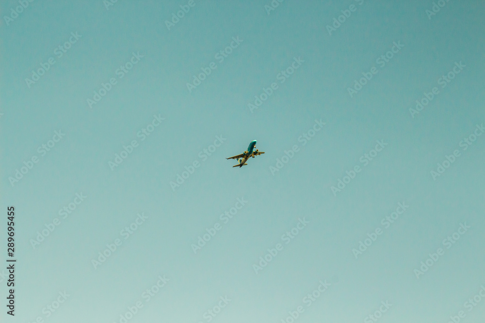 A white airplane flying in a clear pale blue sky. A white airplane flying in a clear pale blue sky.