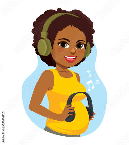 Beautiful black pregnant woman holding headphones on her belly while enjoying music