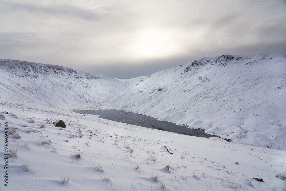 Sun fighting through the cloud over Hayeswater Tarn below the summits of High Street, Thronthwaite Crag and Gray Crag near Hartsop.