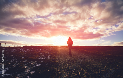 Canvas Print The silhouette of a hiker walking into the sunset across a moorland trail