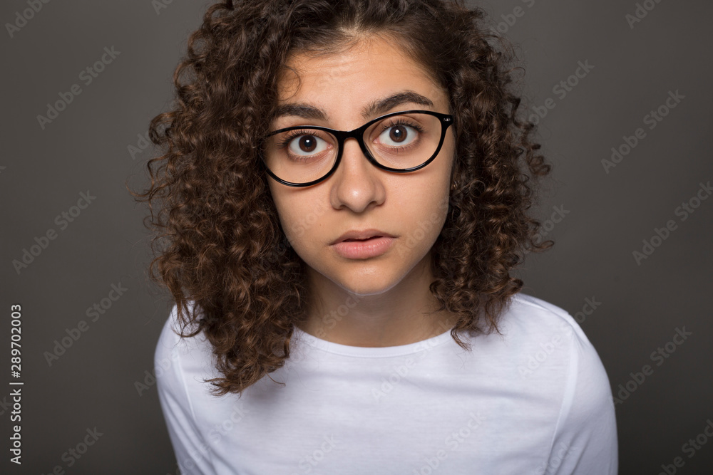 Portrait of an Indian girl in glasses looking at the camera on a black background. Close-up of an interesting and curious woman. Portrait of an Indian girl in glasses looking at the camera on a black background. Close-up of an interesting and curious woman.