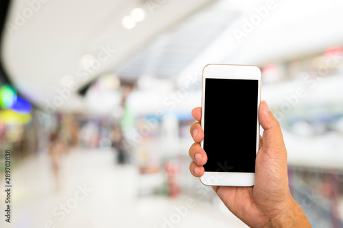 Hand hold black smartphone on blur shopping mall background