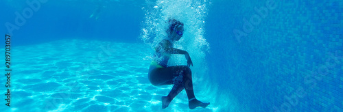 Horizontal underwater photography girl falling in blue water of swimming pool