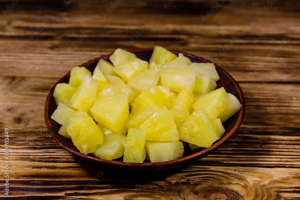 Ceramic plate with chopped canned pineapple on wooden table Ceramic plate with chopped canned pineapple on wooden table