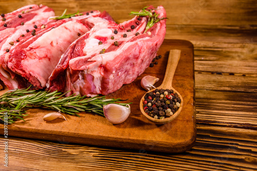 Raw pork ribs with spices, garlic and rosemary on a cutting board