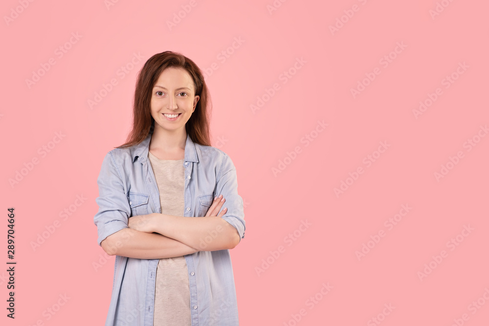 Cute positive red-haired young girl posing on a pink background with hands clasped on her chest. Young charming woman advertises home goods. Advertising space Cute positive red-haired young girl posing on a pink background with hands clasped on her chest. Young charming woman advertises home goods. Advertising space