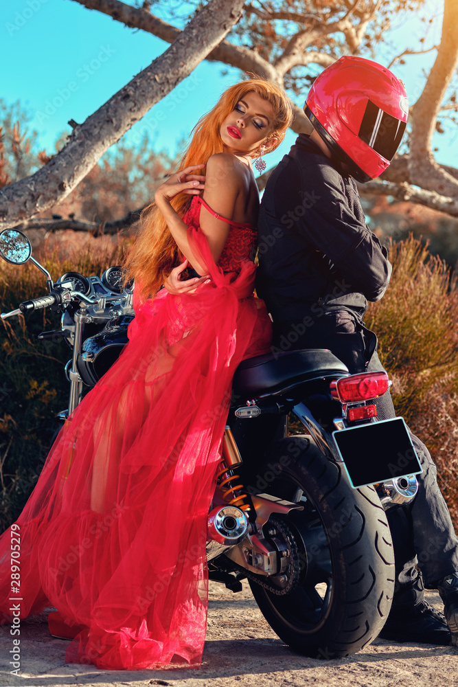 Woman and man sitting on motorcycle posing on nature Woman and man sitting on motorcycle posing on nature