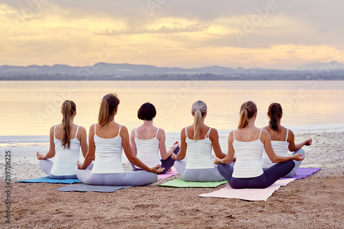 Back view women sitting in lotus pose meditating outdoors