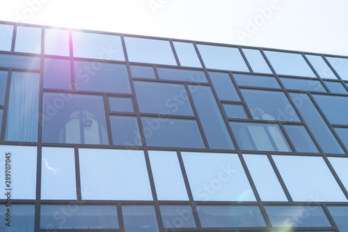 Minimalism in street photography. Glass office building against the blue sky. Modern design and straight lines - urban texture.