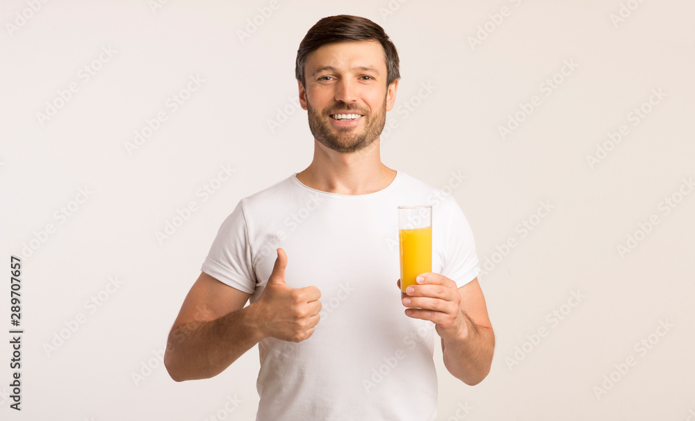 Man Holding Glass Of Juice Gesturing Thumbs-Up In Studio Man Holding Glass Of Juice Gesturing Thumbs-Up In Studio