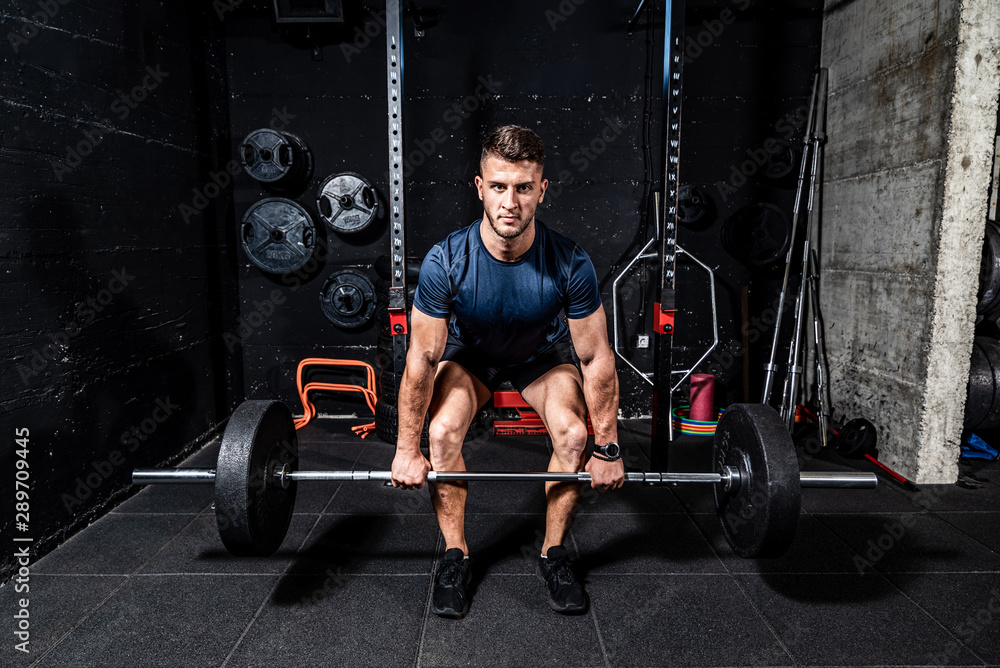 Young strong fit muscular sweaty man with big muscles doing heavy barbell weight lifting workout cross training in the gym real people Young strong fit muscular sweaty man with big muscles doing heavy barbell weight lifting workout cross training in the gym real people