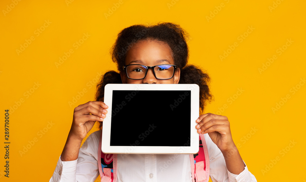 African American Schoolgirl Hiding Behind Tablet Blank Screen, Yellow Background African American Schoolgirl Hiding Behind Tablet Blank Screen, Yellow Background