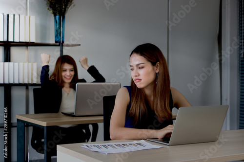 Fotografie Angry envious Asian business woman looking successful competitor colleague in office