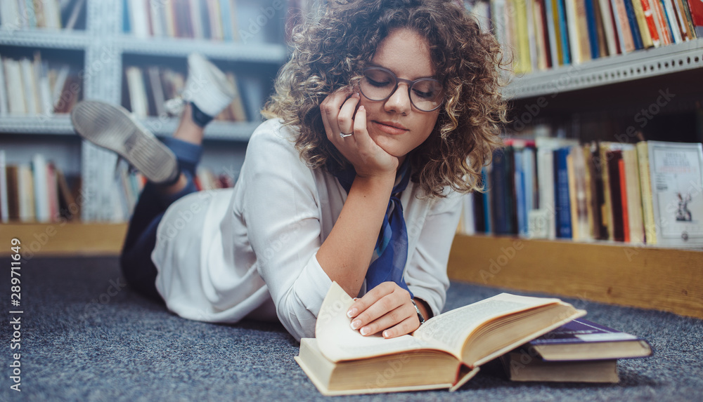 Young woman reading a book in library. Young student learning. Young woman reading a book in library. Young student learning.