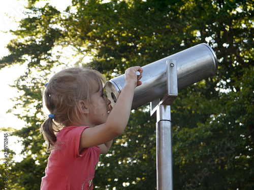 Girl looking through a telescope in the open air.