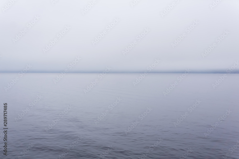 cold body of water with a distant shore hidden by fog