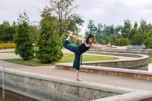 young girl in the park is doing yoga asana