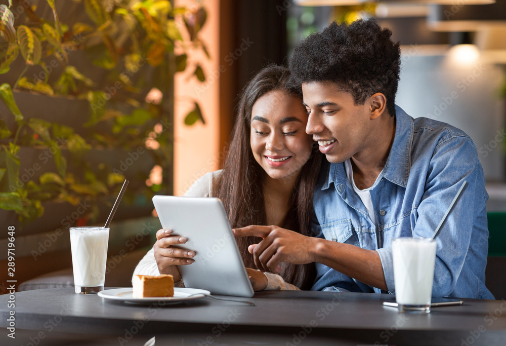 Teen couple in cafe using digital tablet and laughing Teen couple in cafe using digital tablet and laughing