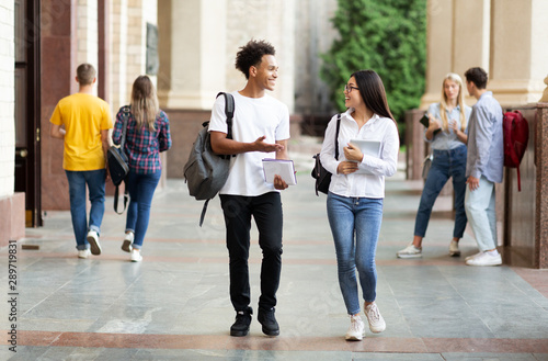 Diverse classmates chatting, walking after classes outdoors