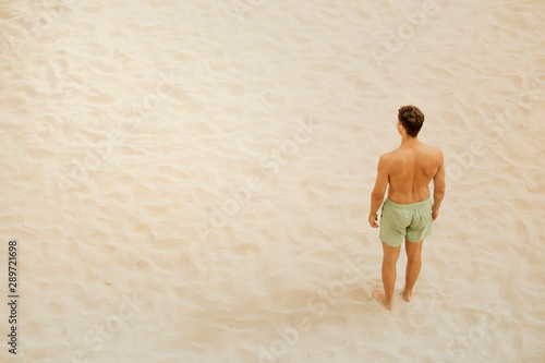 aerial view of a man on the beach, standing on the fine sand of the beach. look at the horizon, wait for something.