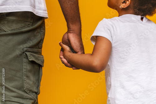 фотографія Little african girl holding her daddy hand and looking at him